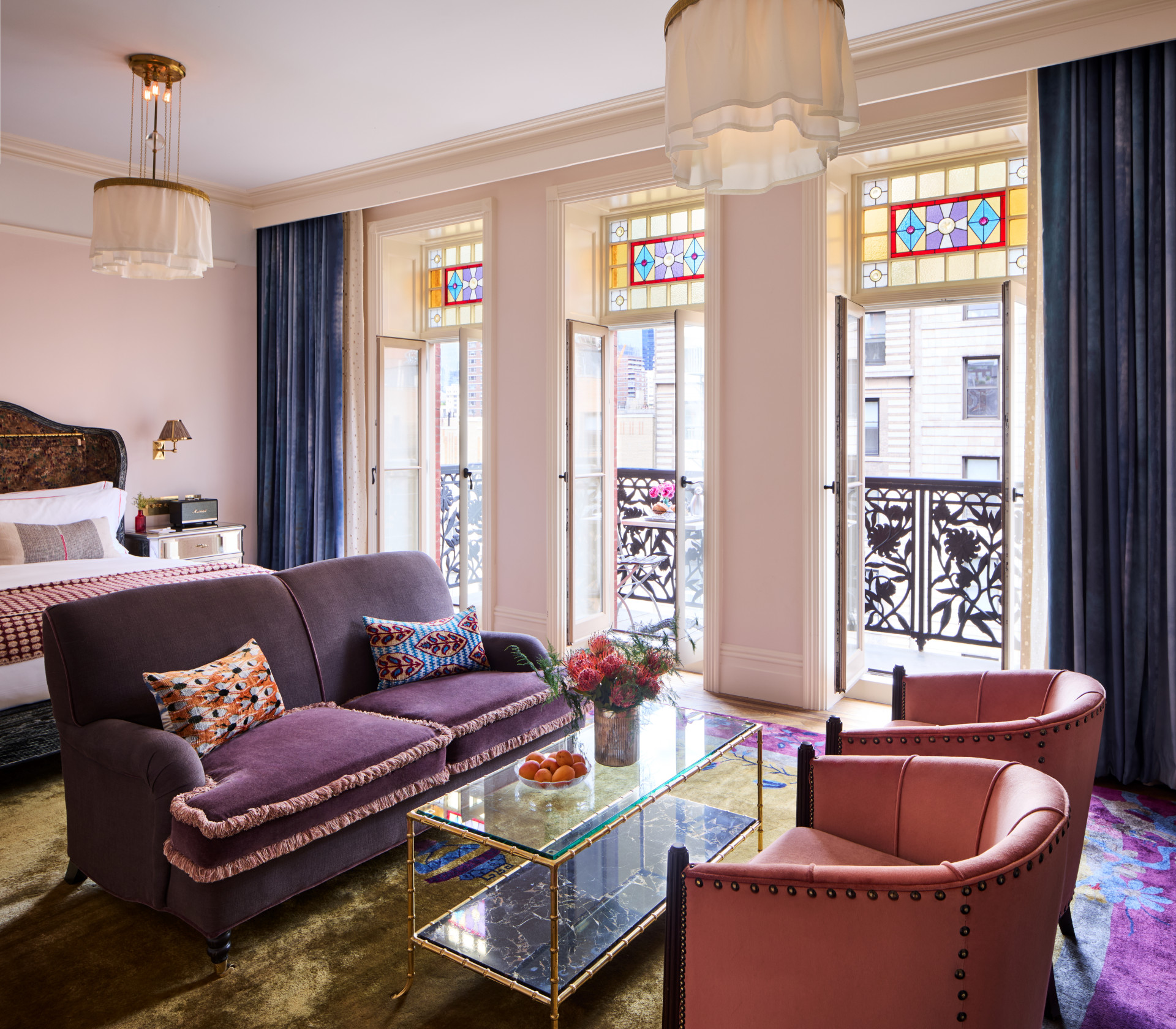 A wide view of a hotel room with a sofa, chairs, and a balcony door