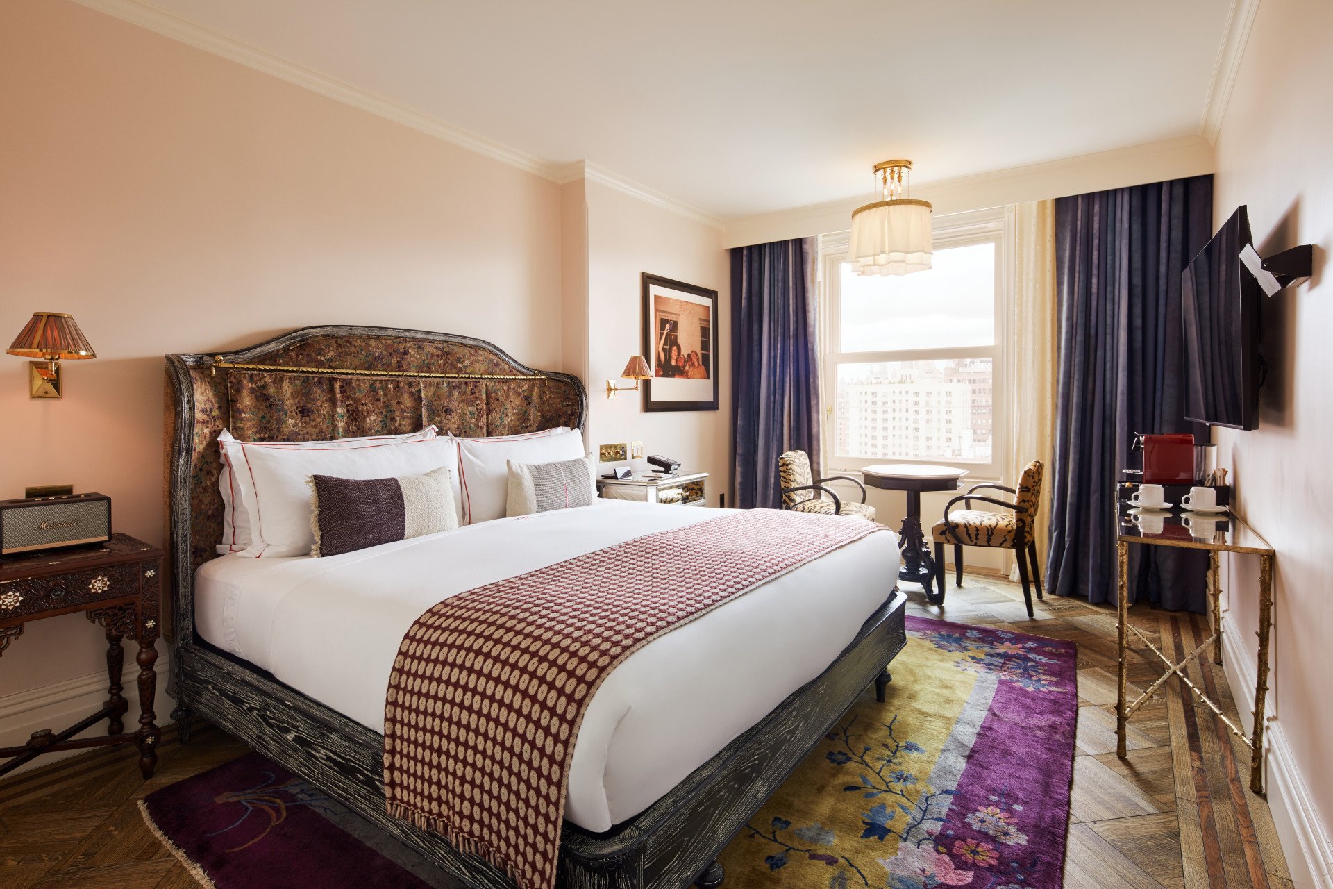 A wide view of a guest room with a large bed, desk, and window.